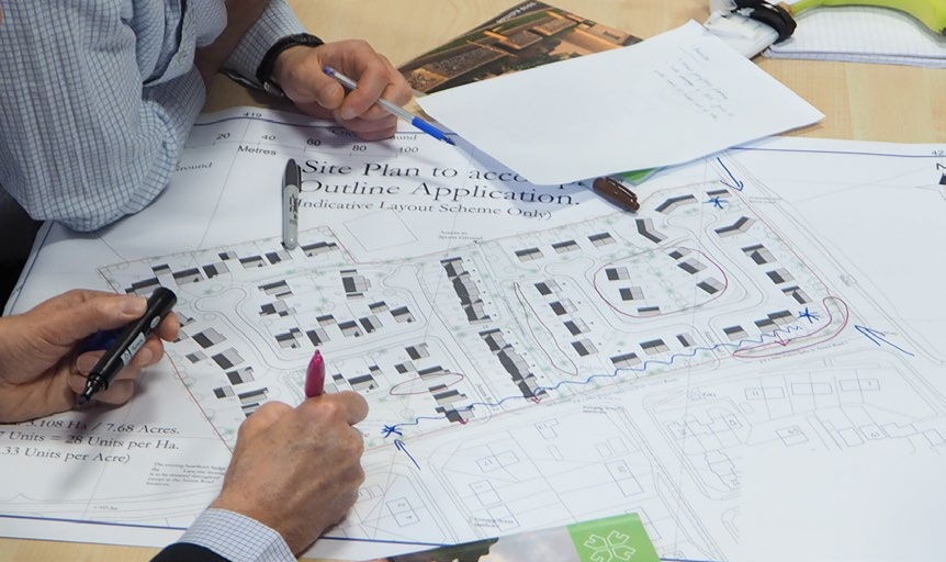 site plan for a housing development laid on a table with two people sat leaning on the table