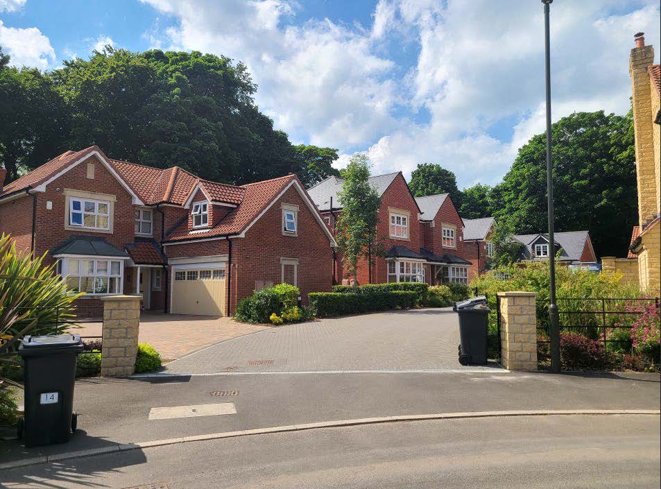 A road leading up to detached houses.