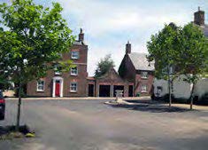 A road turning into a street with houses and trees.